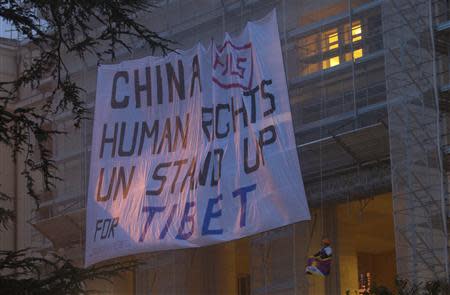 Members of the Students for a Free Tibet organisation display a banner on scaffolding in front of the European headquarters of the United Nations in Geneva October 22, 2013. REUTERS/Denis Balibouse