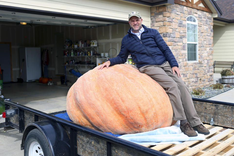 In this Wednesday, Oct. 16, 2019 photo Andy Corbin poses for a photo with his 1,491 pound pumpkin in Cheyenne. Corbin now once again holds the state record for largest pumpkin. (Michael Cummo/The Wyoming Tribune Eagle via AP)