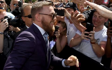 UFC lightweight champion Conor McGregor greets fans as he arrives at Toshiba Plaza - Credit: Getty