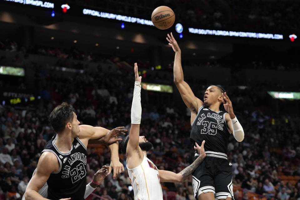 San Antonio Spurs guard Romeo Langford (35) shoots as Miami Heat forward Caleb Martin, center, defends during the first half of an NBA basketball game Saturday, Dec. 10, 2022, in Miami. (AP Photo/Lynne Sladky)