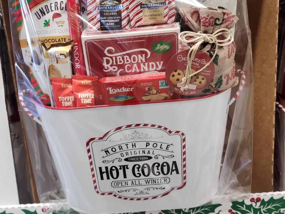 White metal basket filled with candies, toffee, and cookies wrapped in red packaging