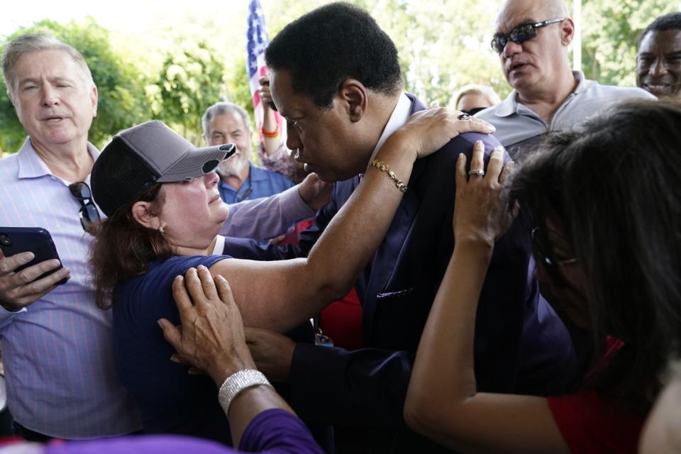 Conservative radio talk show host Larry Elder center right, is hugged by supporter Paulette Melton