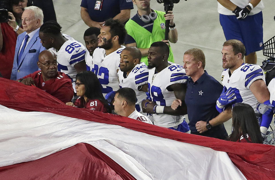 Dallas Cowboys owner Jerry Jones, left, and head coach Jason Garrett, second from right, stand with their players for the national anthem prior to a Week 3 game at Arizona. (AP)