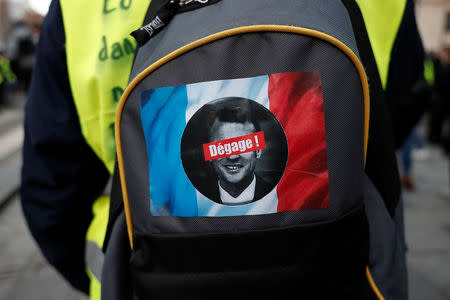 A sitcker with a French flag, a portrait of French President Emmanuel Macron barred with the message "get out" is seen on a bag of a protester wearing a yellow vest in a demonstration by the "yellow vests" movement on the Champs Elysees in Paris, France, December 8, 2018. REUTERS/Benoit Tessier