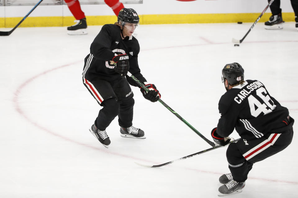 Chicago Blackhawks right wing Patrick Kane, left, looks to pass the puck against defender Lucas Carlsson, right, during NHL hockey practice at Fifth Third Arena on Monday, July 13, 2020, in Chicago. (AP Photo/Kamil Krzaczynski)