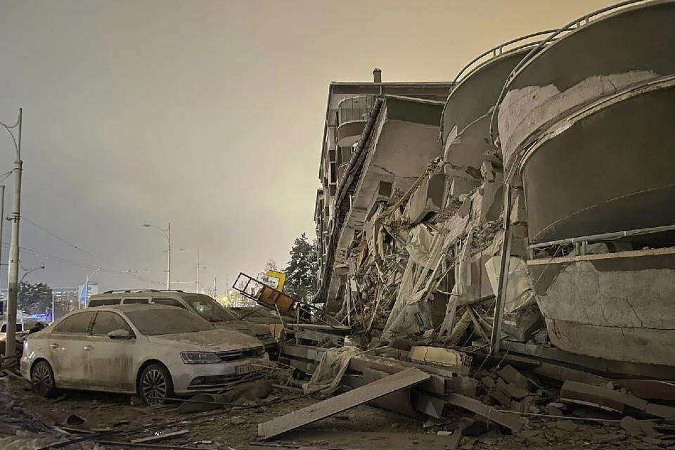 <p>Damaged vehicles sit parked in front of a collapsed building following an earthquake in Diyarbakir, southeastern Turkey, early Monday, Feb. 6, 2023. A powerful quake has knocked down multiple buildings in southeast Turkey and Syria and many casualties are feared. (Depo Photos via AP)</p> 