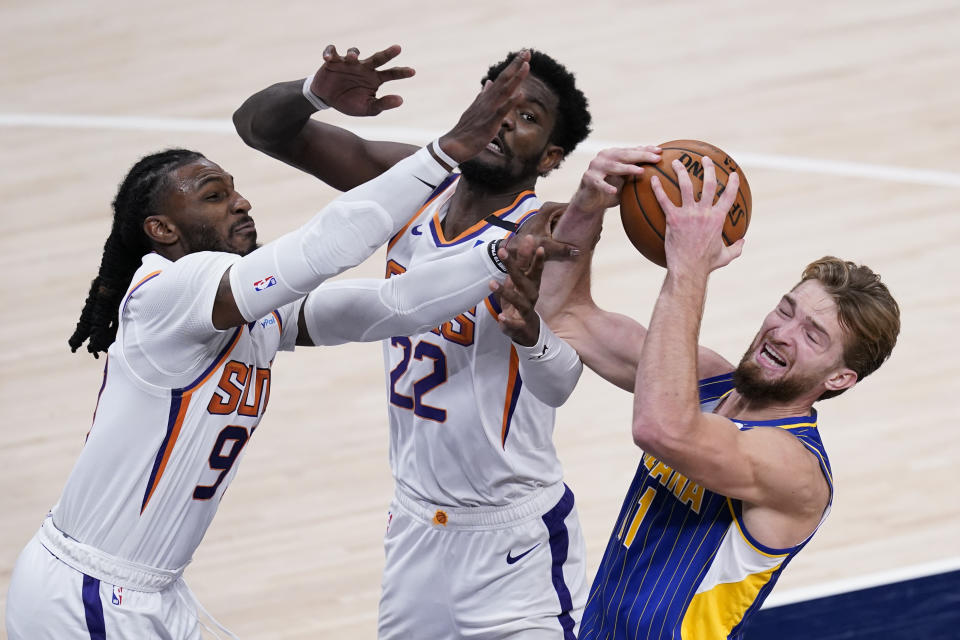 Indiana Pacers' Domantas Sabonis (11) grabs a rebound against Phoenix Suns' Jae Crowder (99) and Deandre Ayton (22) during the second half of an NBA basketball game, Saturday, Jan. 9, 2021, in Indianapolis. (AP Photo/Darron Cummings)