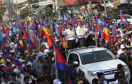 Sam Rainsy (center, R), president of the opposition Cambodian National Rescue Party (CNRP) and party vice-president Kem Sokha (center, L), stand on a vehicle while greeting supporters during a protest in Phnom Penh December 29, 2013. REUTERS/Stringer