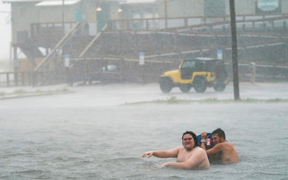 People play in a flooded car park at Navarre Beach in Pensacola Beach, Florida - Gerald Herbert /AP