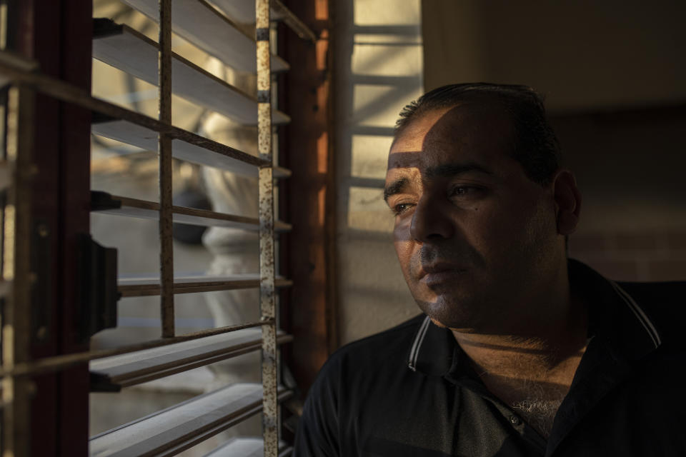 Palestinian Ibrahim Slaieh, who currently has a permit allowing him to work in Israel, poses at his home in Khan Younis, southern Gaza Strip, Wednesday, Aug. 17, 2022. Since last year, Israel has issued over 15,000 permits allowing Palestinians from the Gaza Strip to work in Israel. Their wages are far higher than those available inside Gaza. With Gaza's economy in freefall, these permits are highly coveted and have given an important economic boost to thousands of families. But even Israel acknowledges the system is a powerful tool to preserve calm or — as critics say — control. (AP Photo/Fatima Shbair)