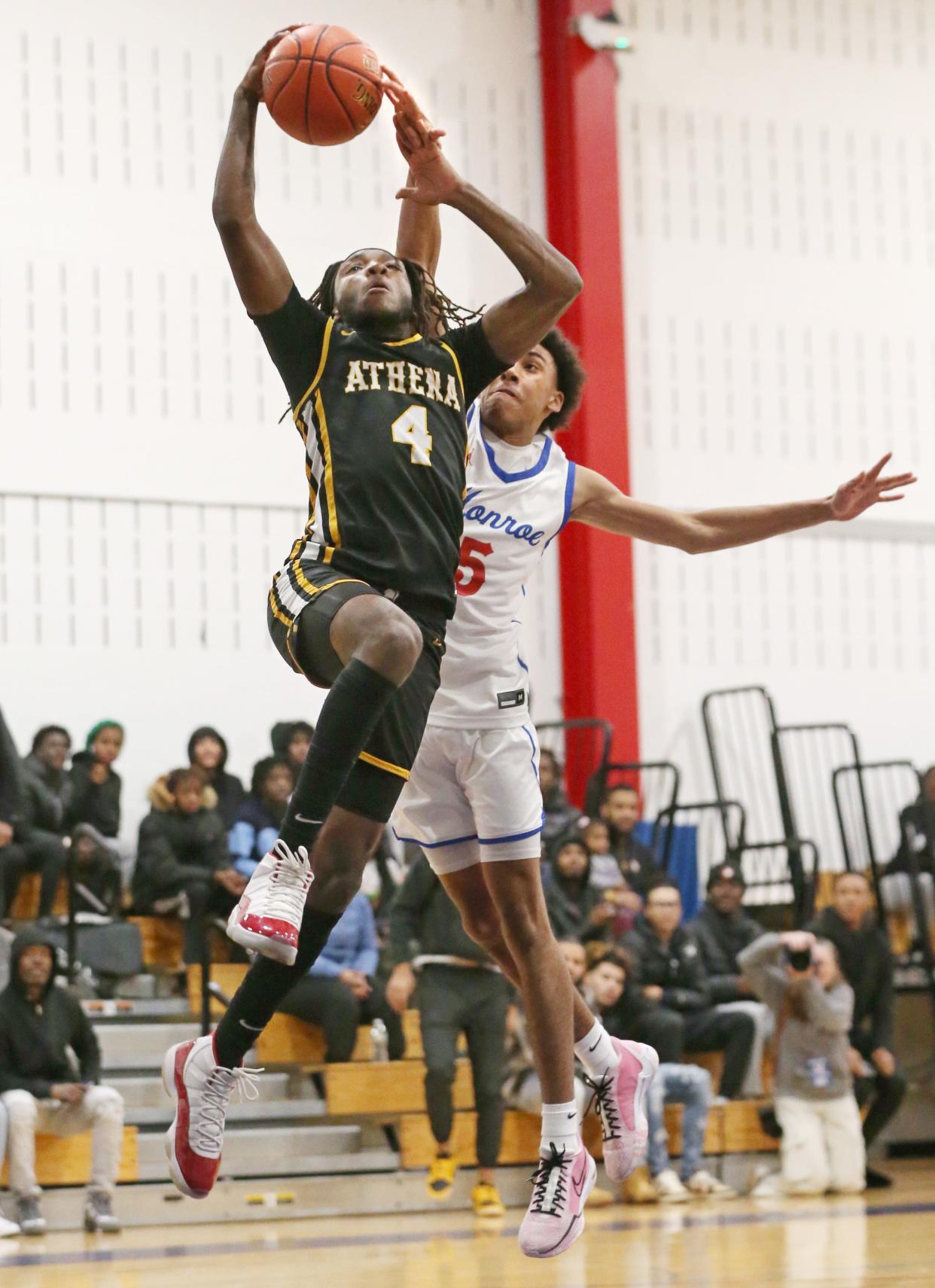 Greece Athena's Zacarr Johnson is fouled by Monroe's Marcus Freeman as he drives to the basket on a fast break in the opening quarter during their Section V boys basketball game Monday, Dec. 18, 2023 at James Monroe High School in Rochester. Athena won the battle of the unbeaten teams, 84-66.