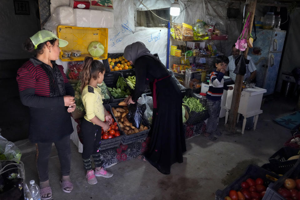 A Syrian woman with her children buy fruits and vegetables at makeshift shop inside a tent at a refugee camp in the town of Bar Elias, in the Bekaa Valley, Lebanon, July 7, 2022. The Lebanese government’s plan to start deporting Syrian refugees has sent waves of fear through vulnerable refugee communities already struggling to survive in their host country. Many refugees say being forced to return to the war shattered country would be a death sentence. (AP Photo/Bilal Hussein)