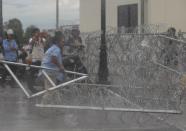 A protester supporting the opposition Cambodia National Rescue Party (CNRP) tries to remove barbed wire barricades during clashes with police near the Royal Palace in central Phnom Penh September 15, 2013. (REUTERS/Samrang Pring)