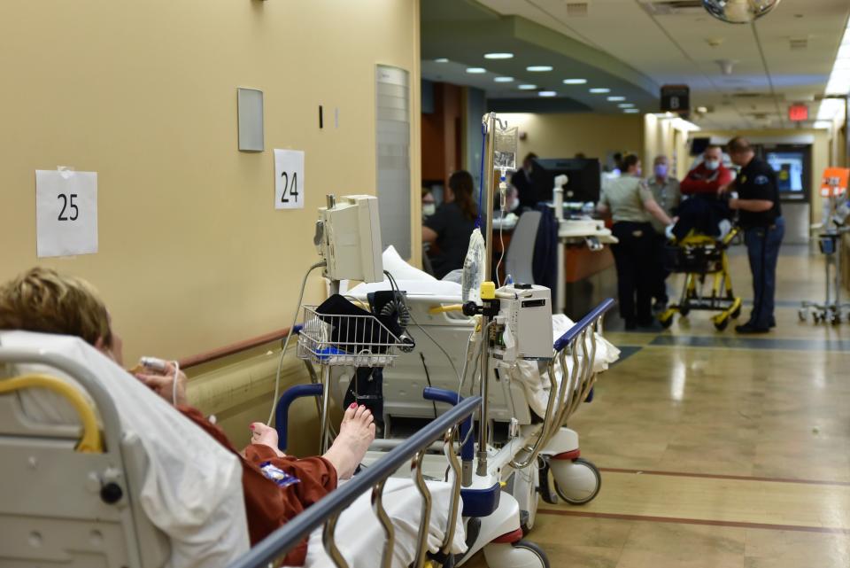 A new patient is brought in by ambulance as other patients are stationed in beds lining some of the hallways in the emergency area of Sparrow Hospital.