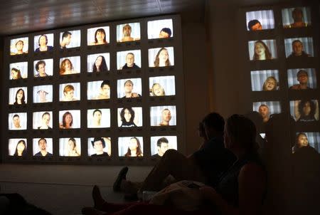 Visitors sit and watch an exhibit at the cutting edge Museum of Old and New Art (MONA) located on the outskirts of the capital city of Hobart December 31, 2014. REUTERS/Matt Siegel