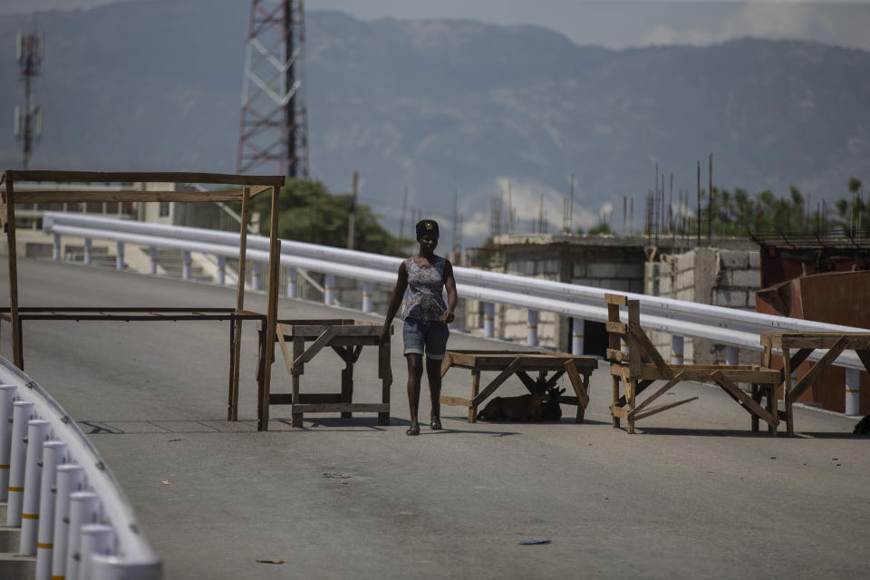 A woman walks past a barricade set up by gang members in Croix-des-Missions, north of Port-au-Prince, Haiti, Thursday, April 28, 2022. Gangs have forced schools, businesses and hospitals to close as they raid new neighborhoods, seize control of the main roads connecting the capital to the rest of the country and kidnap victims daily. (AP Photo/Odelyn Joseph)