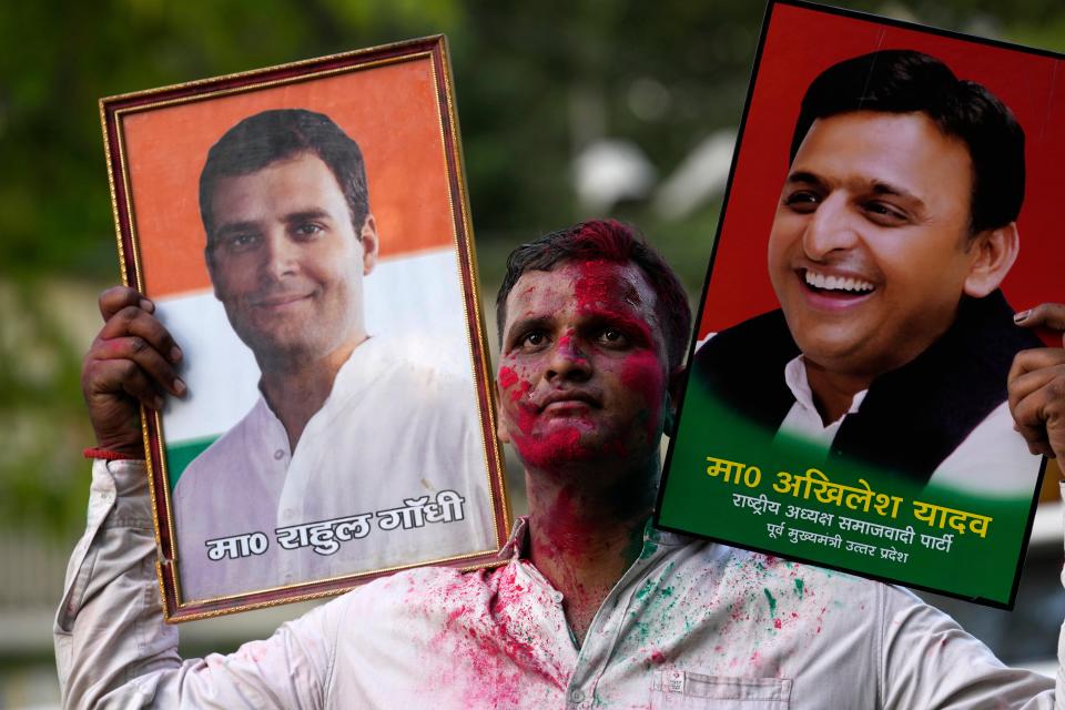 A Samajwadi Party supporter carries portraits of party leader Akhilesh Yadav, right, and Congress Party leader, Rahul Gandhi, as he celebrates his party’s lead during the counting of votes in India’s national election in Lucknow, India, Tuesday, 4 June 2024 (AP)