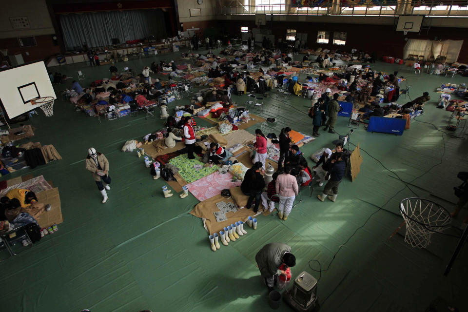 FILE - Local people gather in a school gymnasium being used as an evacuation center for those whose homes were damaged by the tsunami in Ofunato, Japan, on March 16, 2011. The 2011 quake, tsunami and nuclear meltdown in northern Japan provides a glimpse of what Turkey and Syria could face in the years ahead. No two events are alike, but the recent disaster resembles Japan's in the sheer enormity of the psychological trauma, of the loss of life and of the material destruction. (AP Photo/Matt Dunham, File)