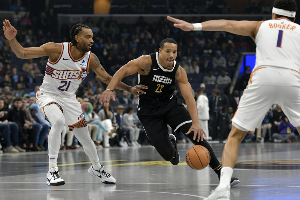 Memphis Grizzlies guard Desmond Bane (22) handles the ball against Phoenix Suns forward Keita Bates-Diop (21) in the first half of an NBA basketball game Friday, Nov. 24, 2023, in Memphis, Tenn. (AP Photo/Brandon Dill)