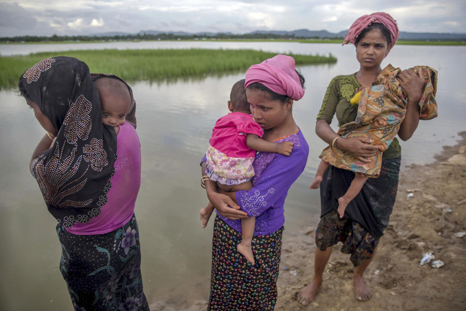 FILE- In this Oct. 18, 2017, file photo, Rohingya Muslim women, who crossed over from Myanmar into Bangladesh, stand holding their sick children after Bangladesh border guard soldiers refused to let them journey towards a hospital and turned them back towards the zero line border in Palong Khali, Bangladesh. A new report by the United Nations children’s agency says the lives and futures of more than 19 million Bangladeshi children are at risk from colossal impacts of devastating floods, cyclones and other environmental disasters linked to climate change. The UNICEF report released Friday, April 5, 2019, said the tally includes Rohingya refugee children from Myanmar who are living in squalid camps in southern Bangladesh. (AP Photo/Dar Yasin, File)