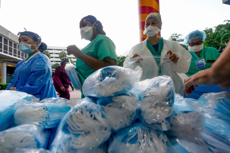 FILE – Healthcare workers line up for free personal protective equipment in front of murals by artist Romero Britto at Jackson Memorial Hospital, Tuesday, Sept. 22, 2020, in Miami. Some states that stockpiled millions of masks and other personal protective equipment during the coronavirus pandemic are now throwing the items away.(AP Photo/Wilfredo Lee, File)