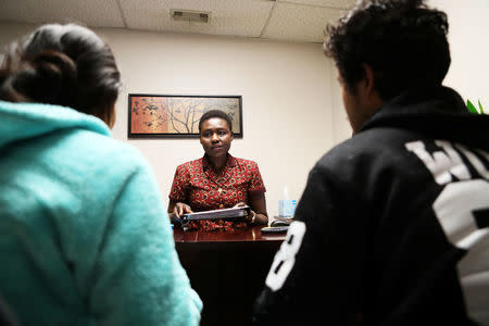 Amy Longa looks over paper work with Wimber Htoo (R) and Htoo Lwae Say (L) at the IRC office in Garden City, Kansas, U.S., March 26, 2018. Picture taken March 26, 2018. REUTERS/Adam Shrimplin