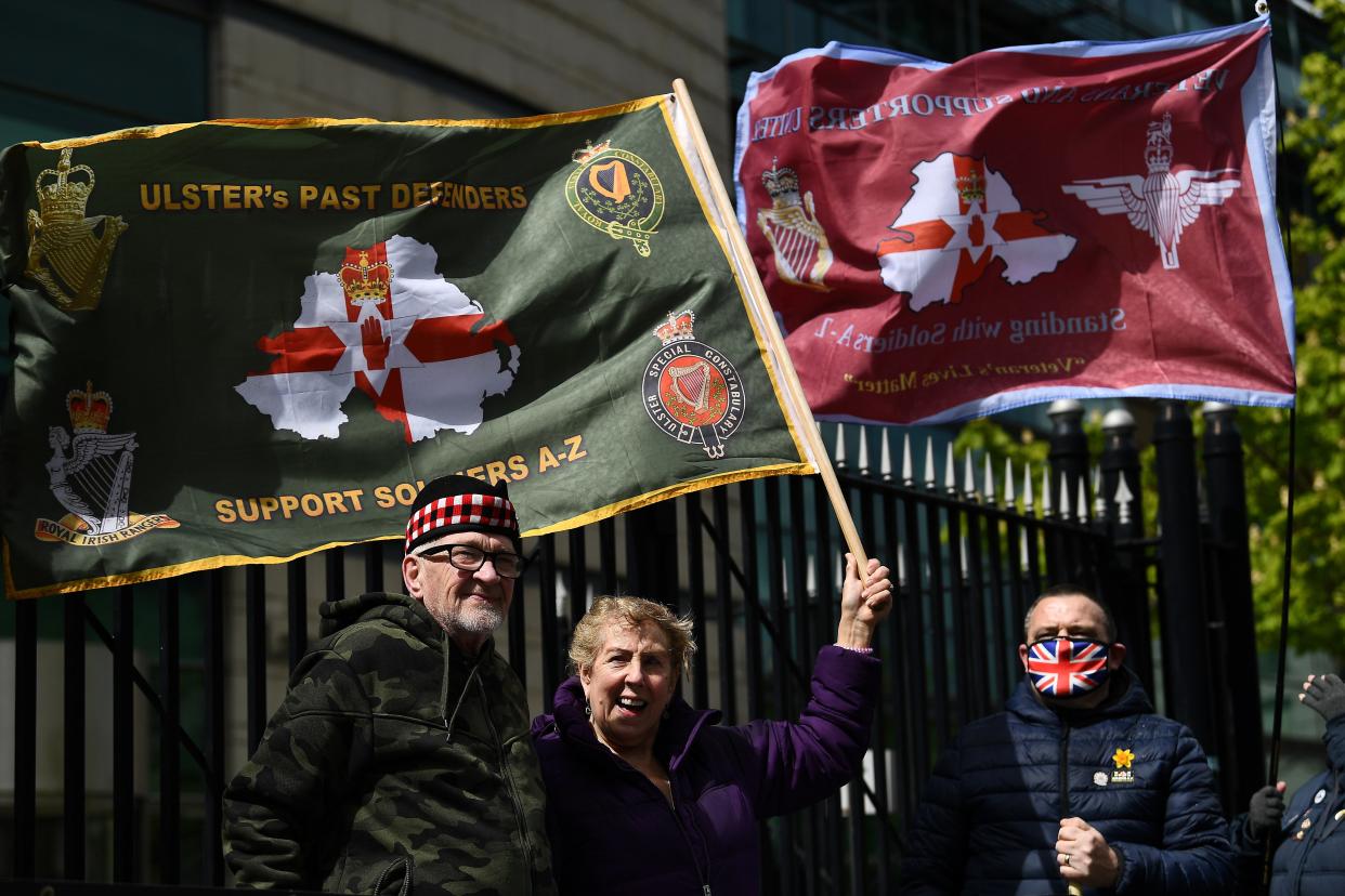 <p>People hold flags outside Belfast’s Laganside Courts during the trial into the 1972 killing of official IRA member Joe McCann, on Tuesday (4 May)</p> (Reuters)