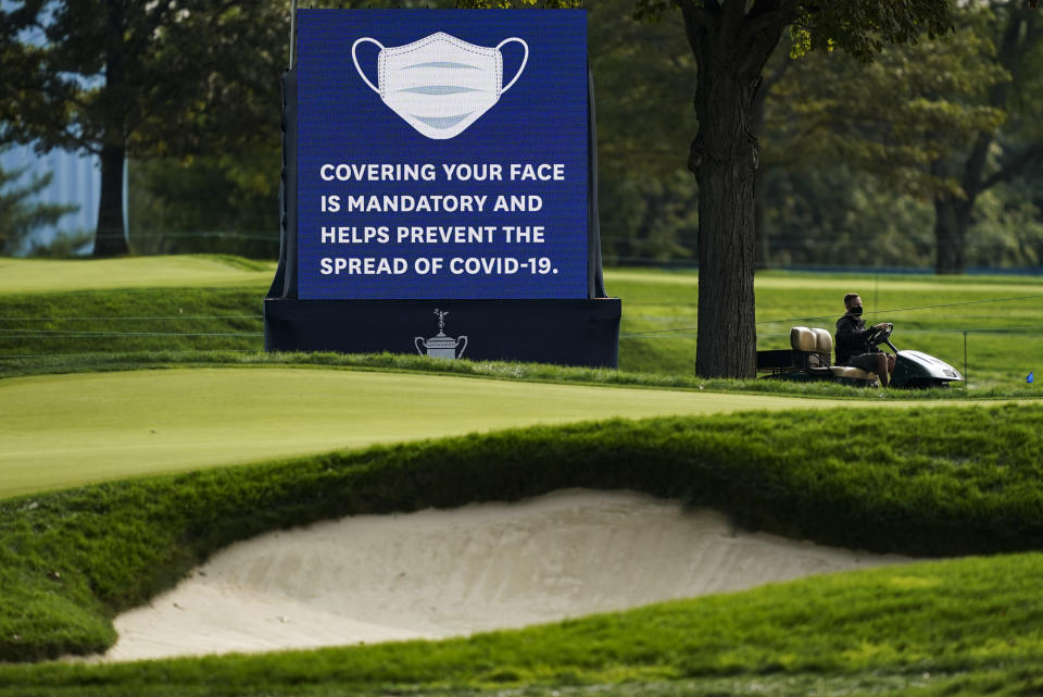 A sign urging COVID-19 prevention practices is displayed beside the 12th fairway during practice before the U.S. Open Championship golf tournament at Winged Foot Golf Club, Tuesday, Sept. 15, 2020, in Mamaroneck, N.Y. (AP Photo/John Minchillo)