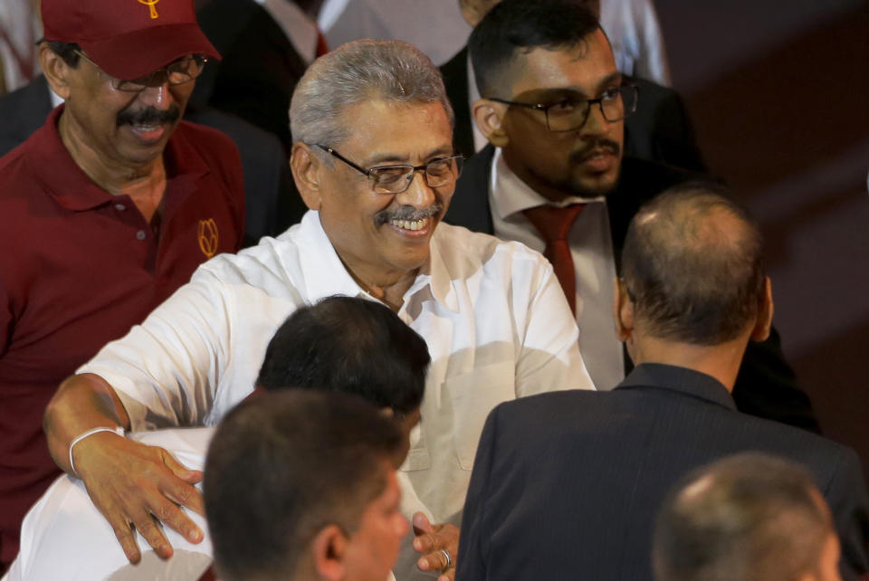 FILE - In this Aug. 11, 2019, file photo, former Sri Lankan Defense Secretary Gotabaya Rajapaksa, center, is embraced by his younger brother Basil during a party convention held to announce the presidential candidacy in Colombo, Sri Lanka. Gotabaya is a feared former defense official accused of human rights abuses and crushing critics, but to many Sri Lankans, he is the leader most needed after last April’s Easter bomb attacks that killed more than 250 people. (AP Photo/Eranga Jayawardena, File)
