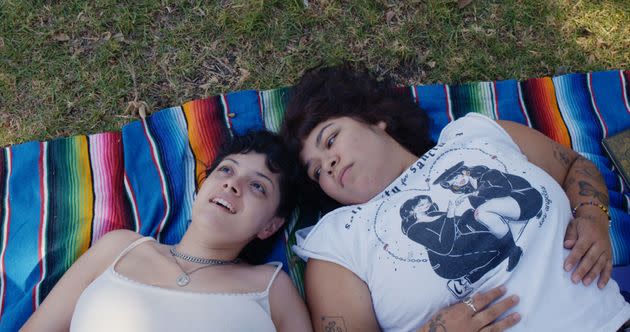 Doris Muñoz and Jacks Haupt lay on a multicolored blanket in the grass, in a scene from the documentary 