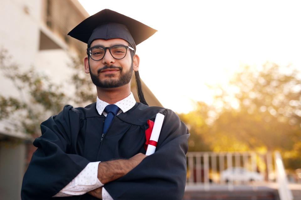 A college grad looks proud holding their diploma