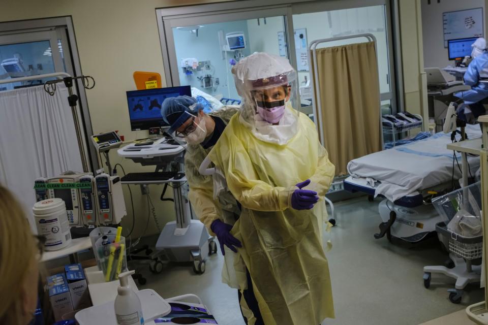 Nurse helps doctor put on personal protective equipment