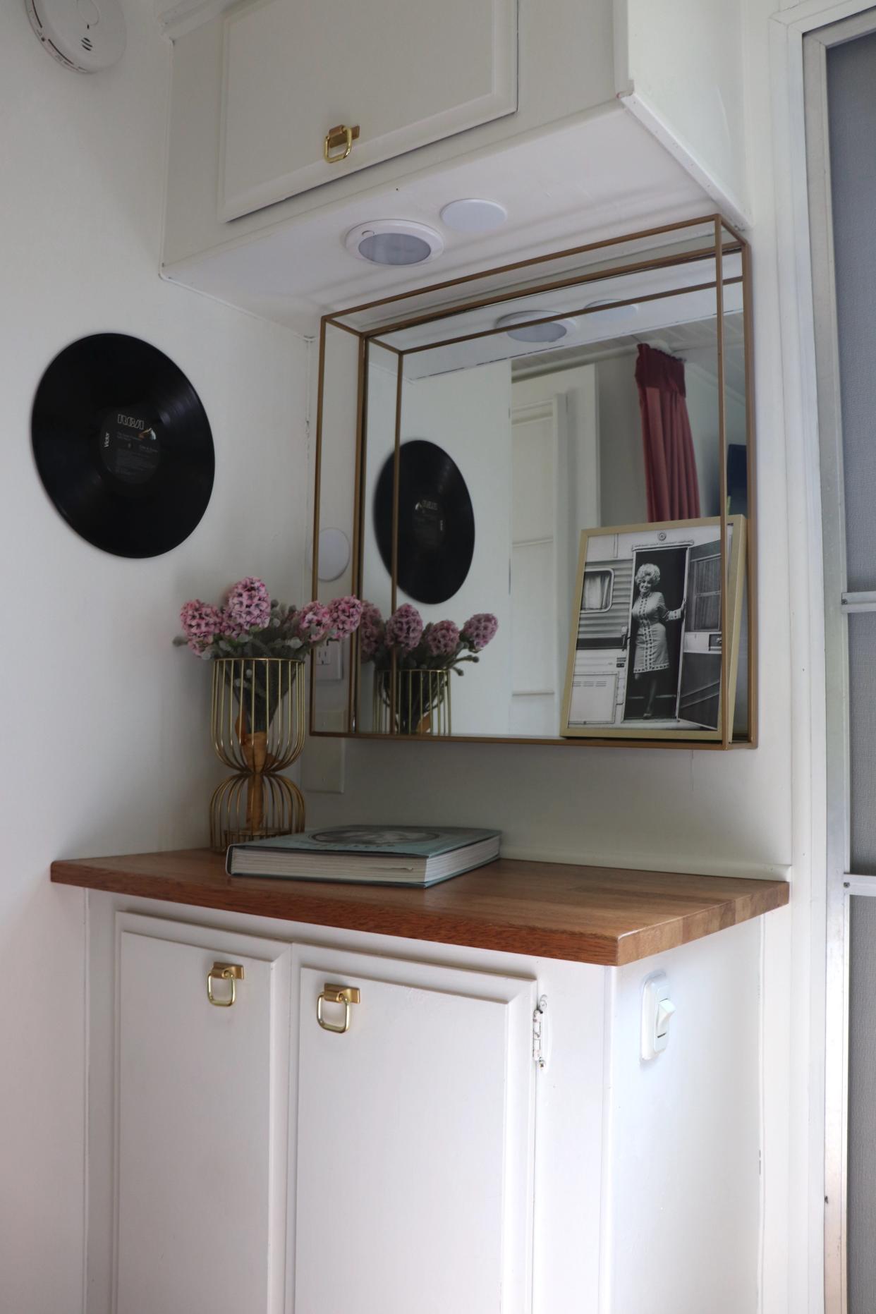 An area with a cabinet and a mirror in a Dolly Parton-themed RV