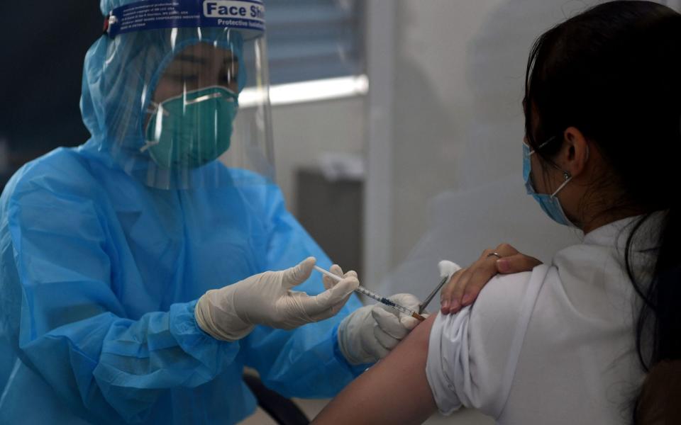 A health worker receives the AstraZeneca vaccine at the National Hospital of Tropical Diseases in Hanoi  - AFP