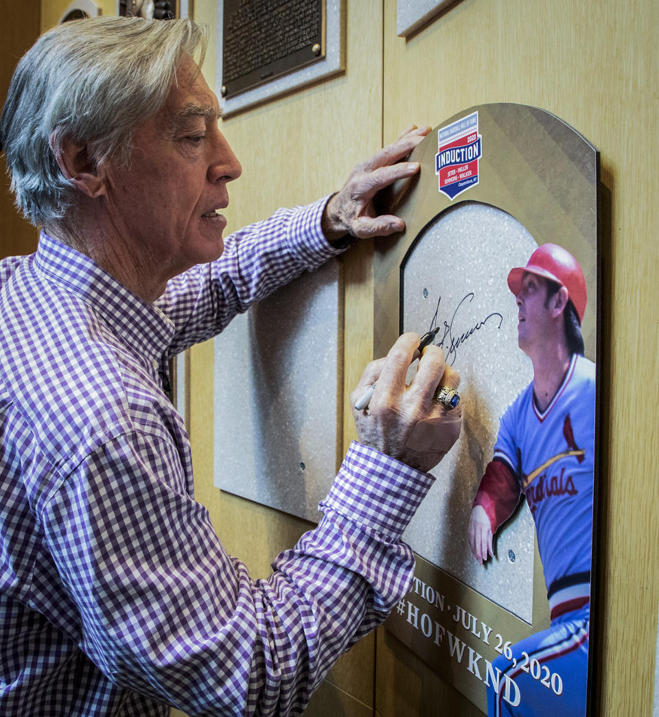 In this image provided by National Baseball Hall of Fame and Museum, Ted Simmons signs where his plaque will hang as the tours the Hall of Fame, Thursday Feb. 27, 2020, in Cooperstown, N.Y. Simmons, a catcher who played for the Cardinals, Brewers and Braves for 21 seasons, was elected to the Hall of Fame by the Modern Baseball Era Committee as part of the Class of 2020. He will be inducted in July. (Milo Stewart, Jr./National Baseball Hall of Fame and Museum via AP)