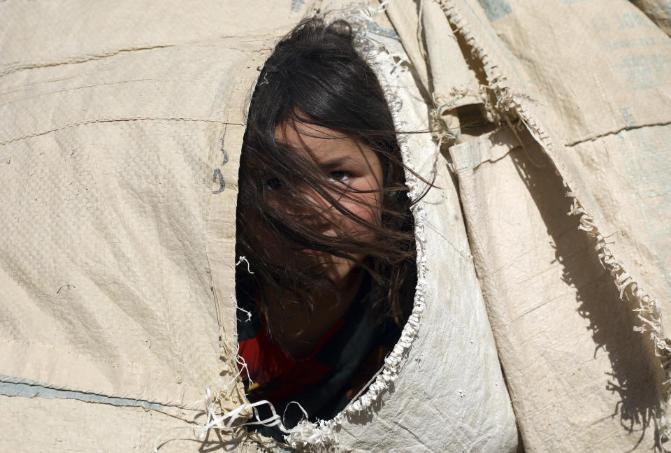 An internally displaced Afghan girl who fled her home due to fighting between the Taliban and Afghan security personnel, peers from her makeshift tent at a camp on the outskirts of Mazar-e-Sharif, northern Afghanistan, Thursday, July 8, 2021. As the Taliban surge through the north of Afghanistan, a traditional stronghold of U.S.-allied warlords and an area dominated by the country’s ethnic minorities, thousands of families are fleeing their homes, fearful of living under the insurgents’ rule. (AP Photo/Rahmat Gul)