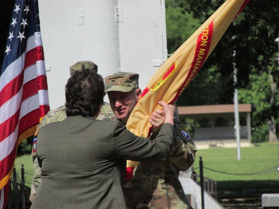 Col. Scott Pence, Fort Bragg's outgoing garrison commander hands the garrison colors to Brenda McCullough, director of the Installation Management Command's readiness division during a command change ceremony Friday, June 24, 2022, at Fort Bragg.