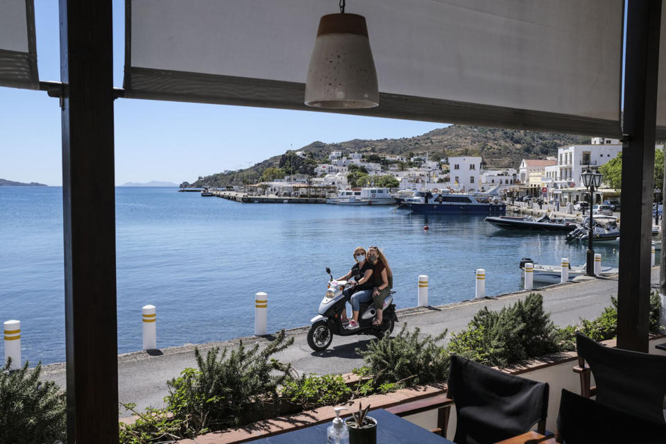 Image: People drive past a local cafe in the main port area of Patmos, Greece. (Byron Smith / Getty Images)