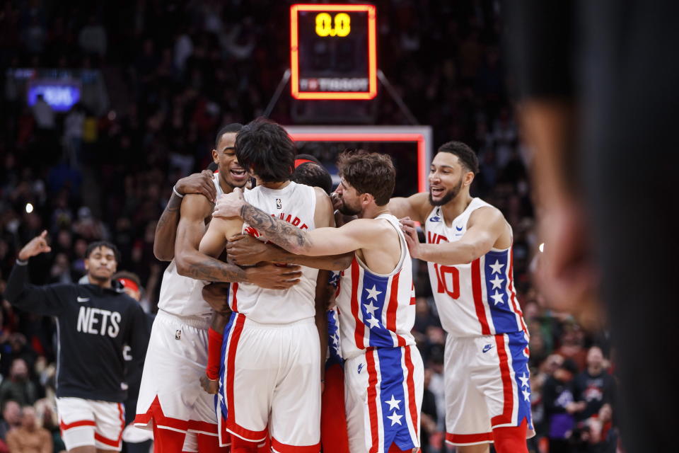 Brooklyn Nets guard Kyrie Irving (obscured) is embraced by teammates after hitting the winning basket against the Toronto Raptors during an NBA basketball game in Toronto, Friday, Dec. 16, 2022. (Cole Burston/The Canadian Press via AP)