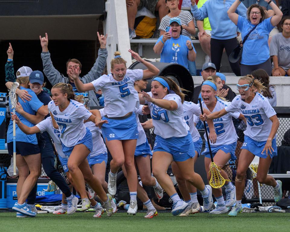 North Carolina defender Gabi Hall (No. 5), attacker Reilly Casey (No. 7), midfielder Ella Little (No. 33) and teammates erupt in celebration and charge the field after coming back from an eight-goal deficit to defeat Northwestern in the semifinals of the NCAA Division I women's lacrosse tournament at Homewood Field, Friday, May 27, 2022, in Baltimore.