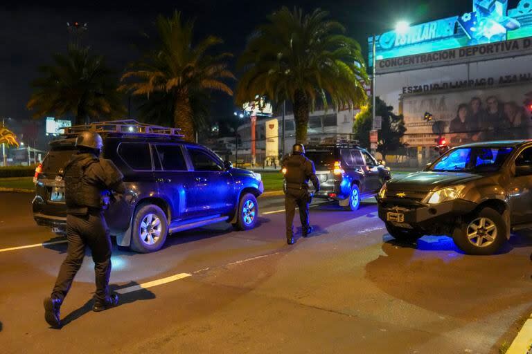 La policía hace guardia ante los vehículos que irrumpieron en la embajada de México en Quito, Ecuador, anoche.  (AP Foto/Dolores Ochoa)