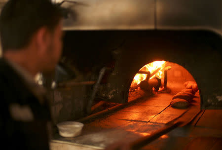 A Palestinian man bakes bread in a firewood oven in Gaza City. REUTERS/Mohammed Salem