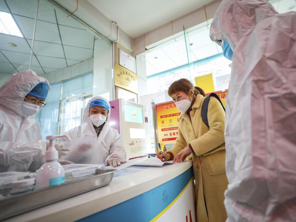 Medical workers in protective gear talk with a woman suspected of being ill with a coronavirus at a community health station in Wuhan in central China's Hubei Province: AP