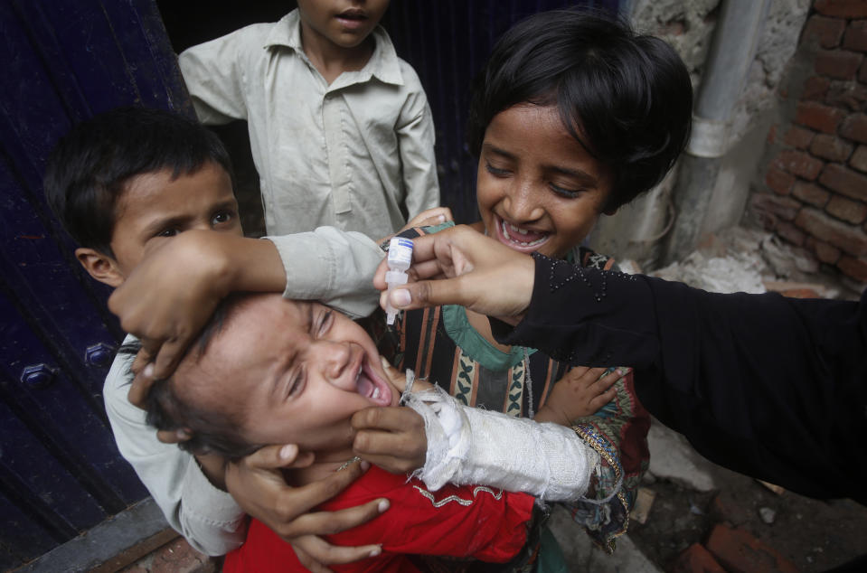 A health worker gives a polio vaccine to a child in Lahore, Pakistan, Tuesday, July 21, 2020. Pakistan resumed vaccinations against polio, months after the drive against this crippling children's disease was halted because the novel coronavirus had overwhelmed the country's health system. (AP Photo/K.M. Chaudary)