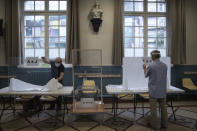 People install plexiglass as part of security measures in a polling station for the second round of the municipal elections, Sunday, June 28, 2020 in Paris. France is holding the second round of municipal elections in 5,000 towns and cities Sunday that got postponed due to the country's coronavirus outbreak. (Joel Saget, Pool via AP)