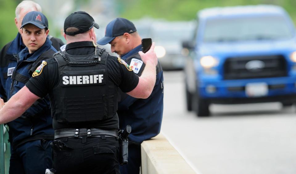 Loudoun County, Va. officials confer on the U.S. 340 bridge below Harper Ferry, W.Va., Sunday as they track a barge carrying construction equipment floating down the Potomac River. They were prepared to close the bridge if the barge headed toward it.