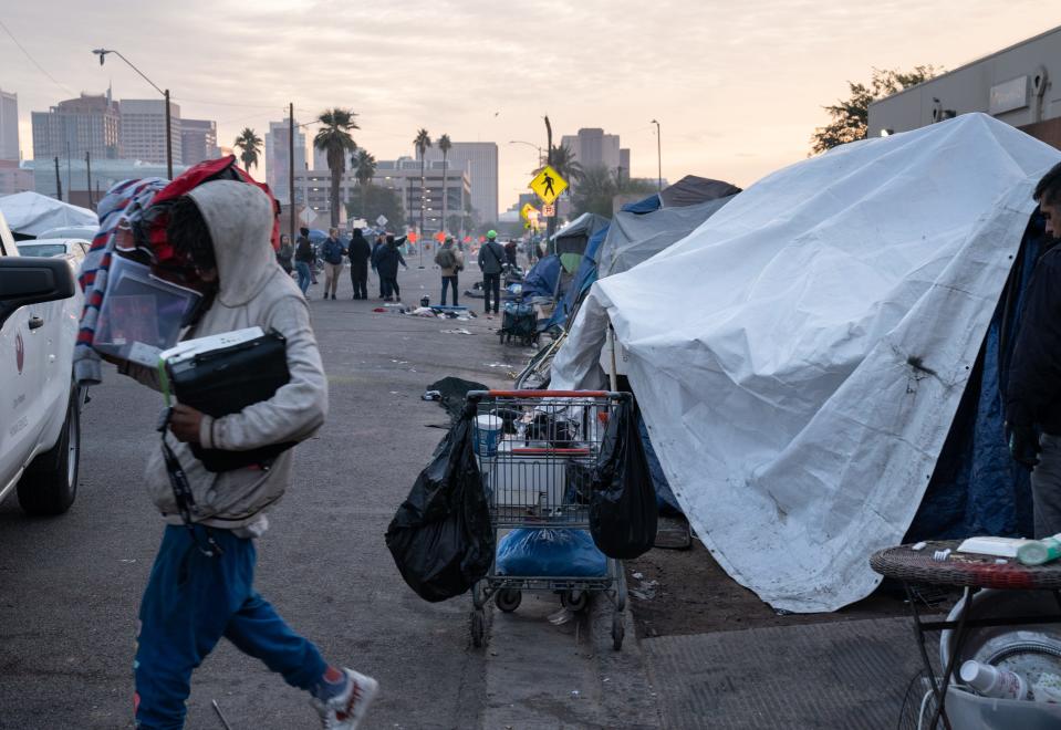 Kevonyae Briggs, left, removes his belongings from his tent on Madison Street (between 12th and 13th Aves.), Dec. 16, 2022, before the City of Phoenix started their enhanced cleanup of the area.
