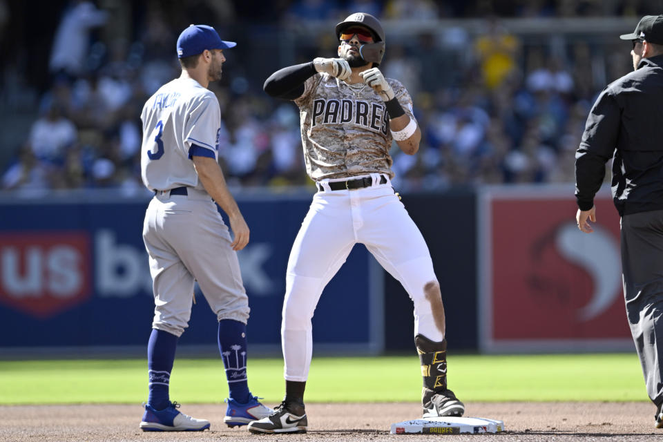 San Diego Padres' Fernando Tatis Jr., center, celebrates next to Los Angeles Dodgers shortstop Chris Taylor after hitting a double during the first inning of a baseball game in San Diego, Sunday, May 7, 2023. (AP Photo/Alex Gallardo)