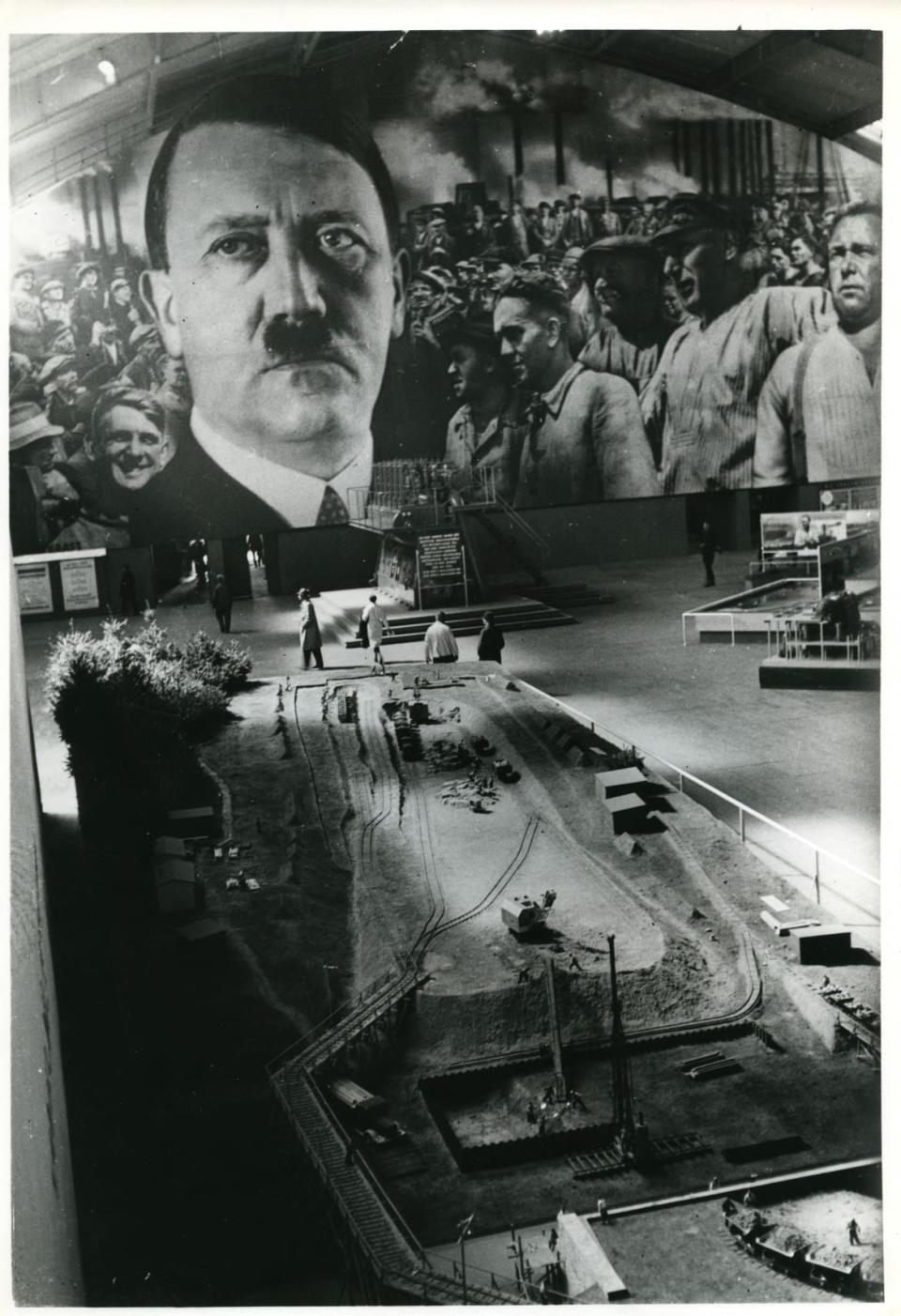 <div class="inline-image__caption"><p><i>Give Me Four Years’ Time</i>! Mining model beneath Hitler mural; people viewing, 1937.</p></div> <div class="inline-image__credit">Courtesy Dittrick Medical History Center, Case Western Reserve University. </div>