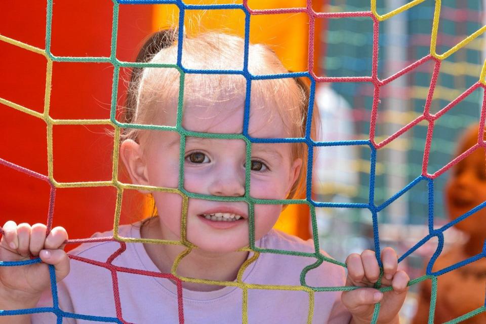 Two-year-old Nora Frankart peaks through the bouncy house, one of the many rides that were included in the fair entry price.